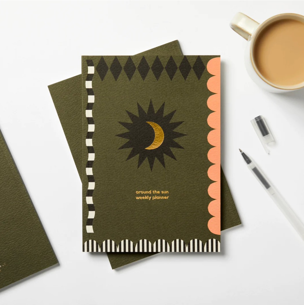 greetings card with a green background, black detailing and gold moon & writing quoting 'around the sun'